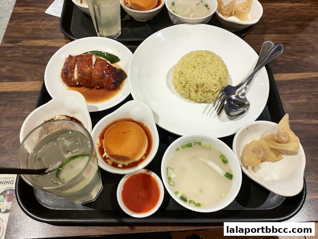A tray of delicious Nam Heong Chicken Rice meal with roasted chicken, fragrant rice, soup, and dessert.
