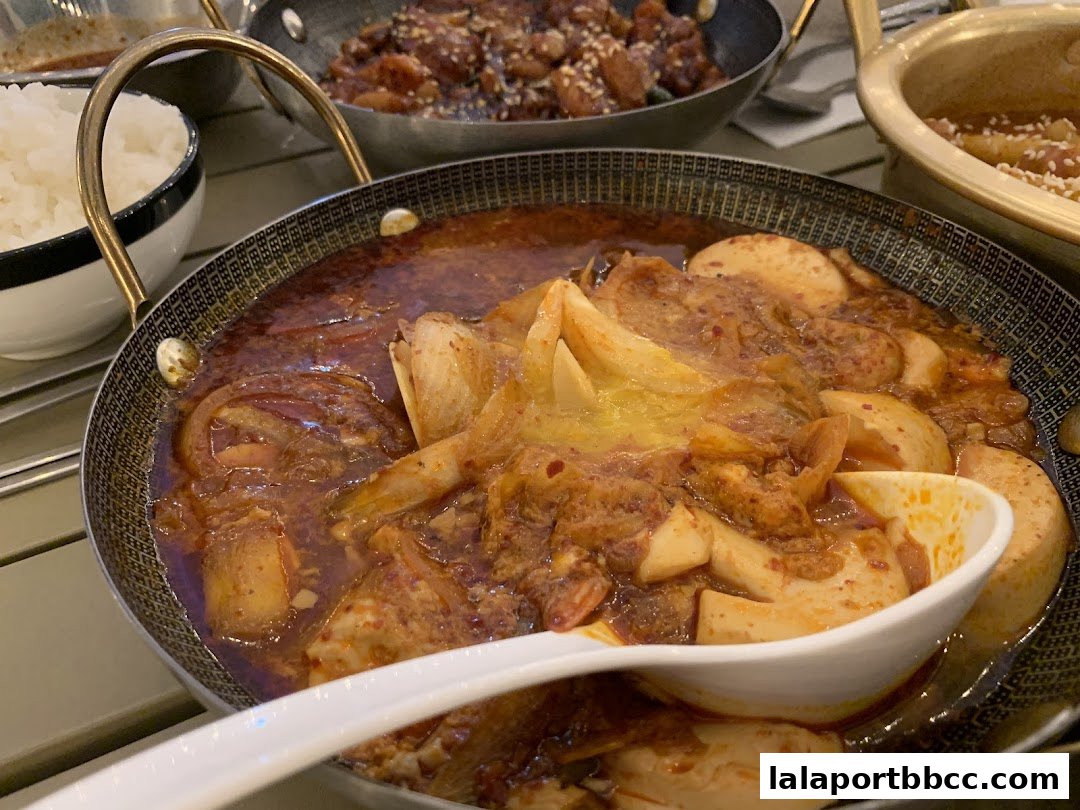 A close-up of a flavorful Korean stew with tofu and meat, served with rice.
