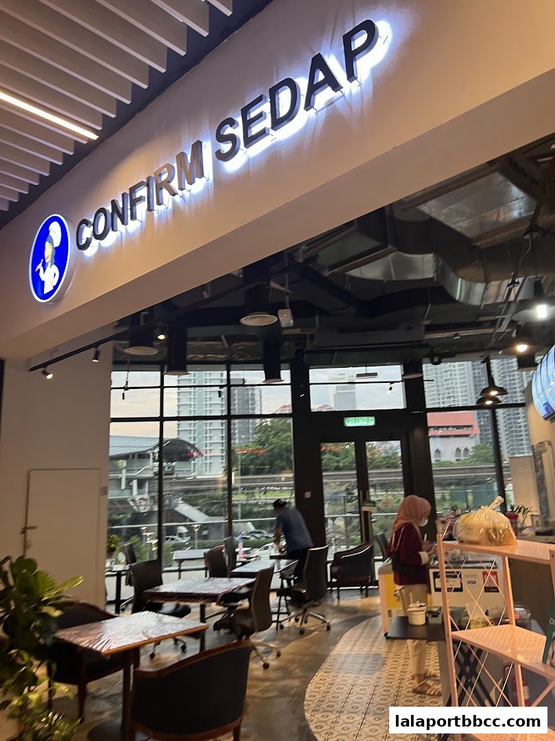 The interior of Confirm Sedap restaurant with tables, chairs, and a view of the city.