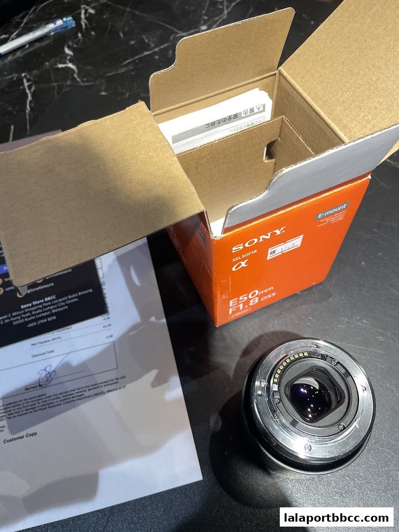 A Sony E-mount camera lens and its packaging are displayed on a table.