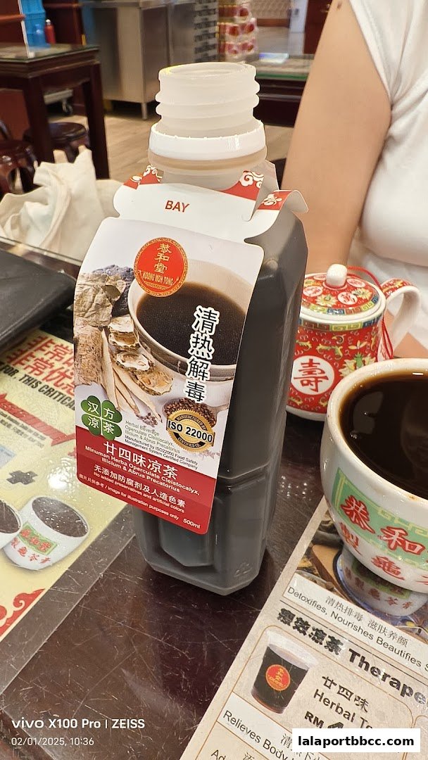 A bottle of herbal tea from Koong Woh Tong with a cup and a small teapot.