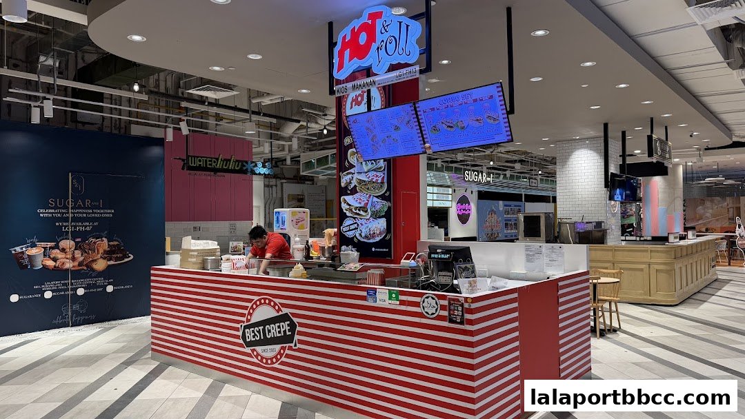 A brightly lit food stall with red and white striped counter, displaying menus and food items.