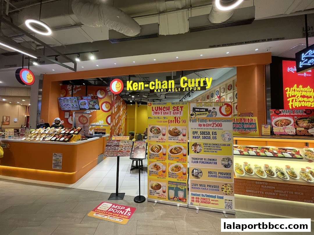 The exterior of Ken-chan Curry, a Japanese curry shop, with a vibrant orange facade and menu displays.