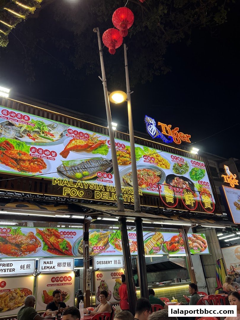 A brightly lit hawker stall at night, showcasing a variety of delicious Malaysian food.