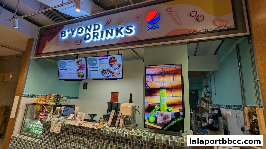 A brightly lit beverage shop counter with a menu displayed on screens and a large advertisement.
