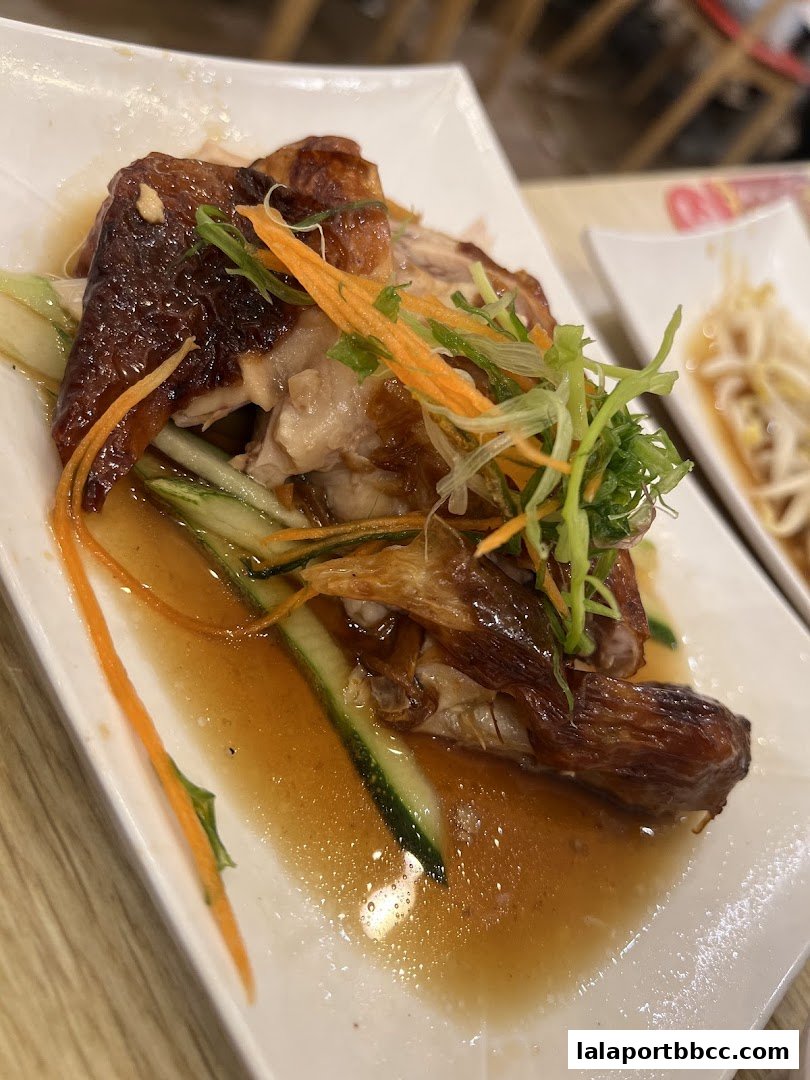 A plate of delicious roasted chicken with cucumber, carrots, and scallions in savory sauce.