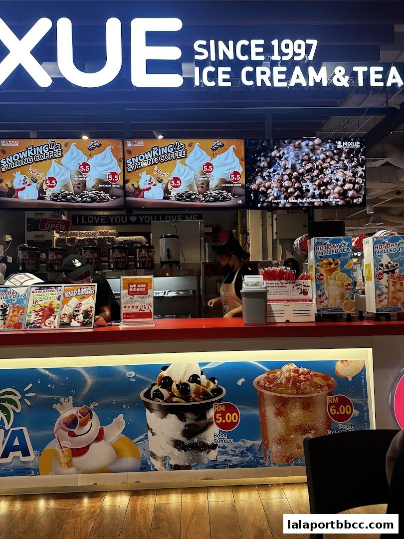 A MIXUE ice cream and tea shop counter with promotional displays and staff.