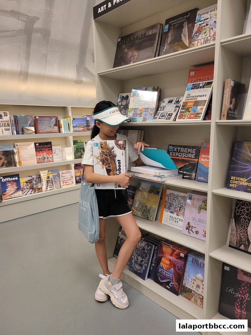 A young girl browses books in a well-lit bookstore, surrounded by shelves of art and photography titles.