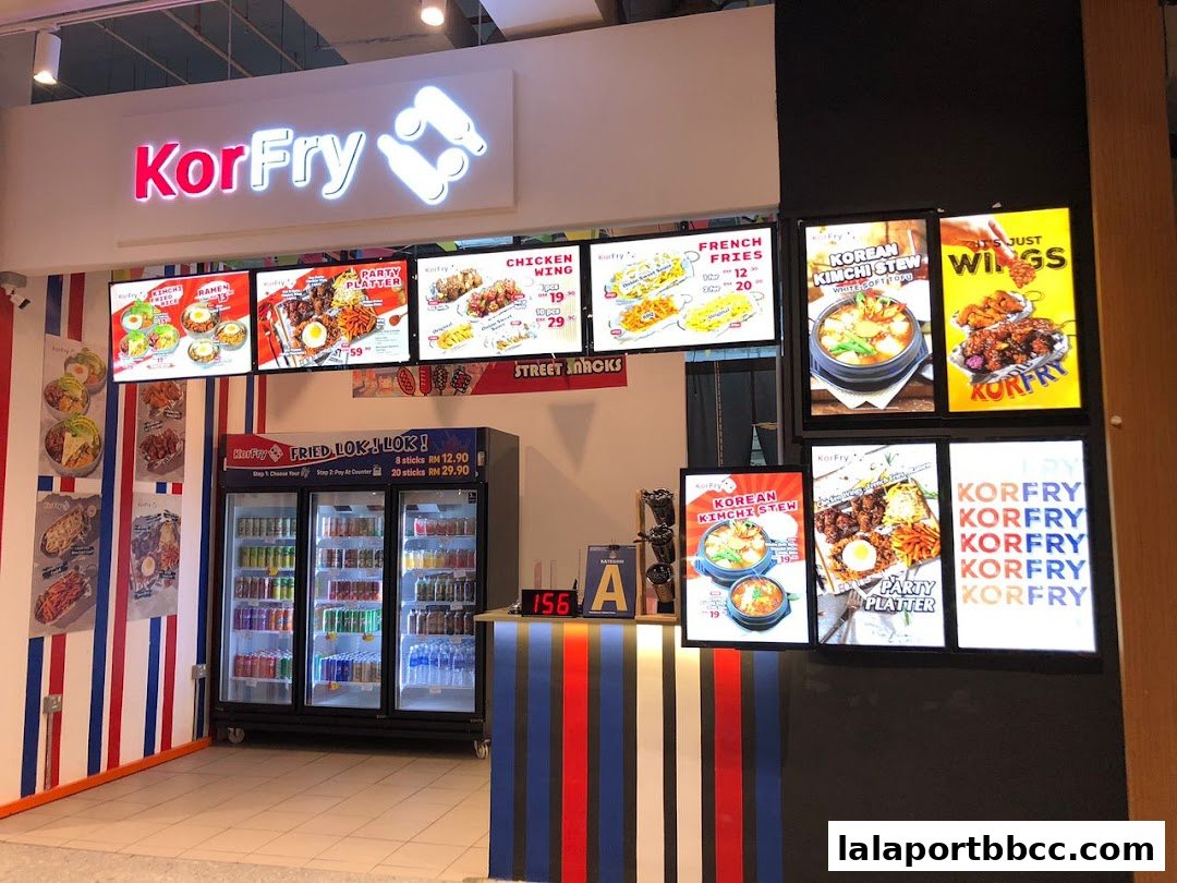 The KorFry shop front displays illuminated menus of Korean fried chicken and stews, with a refrigerated display of drinks.