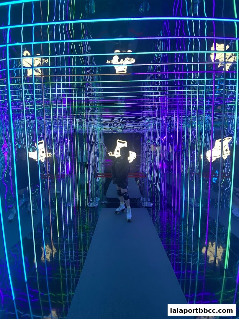 A person on roller skates in a neon-lit tunnel with reflective surfaces.