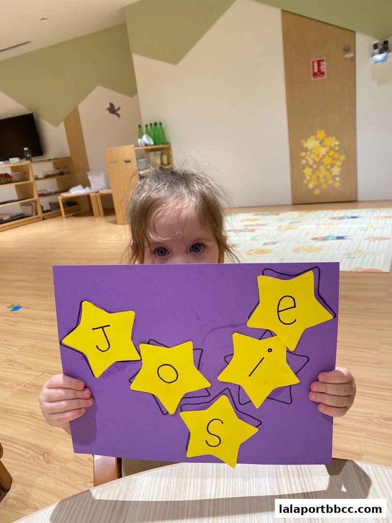 A child holds a purple board with yellow stars spelling out 'Josie'.