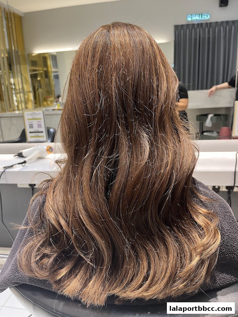 A person's long, wavy, brown hair with highlights, styled in a salon.