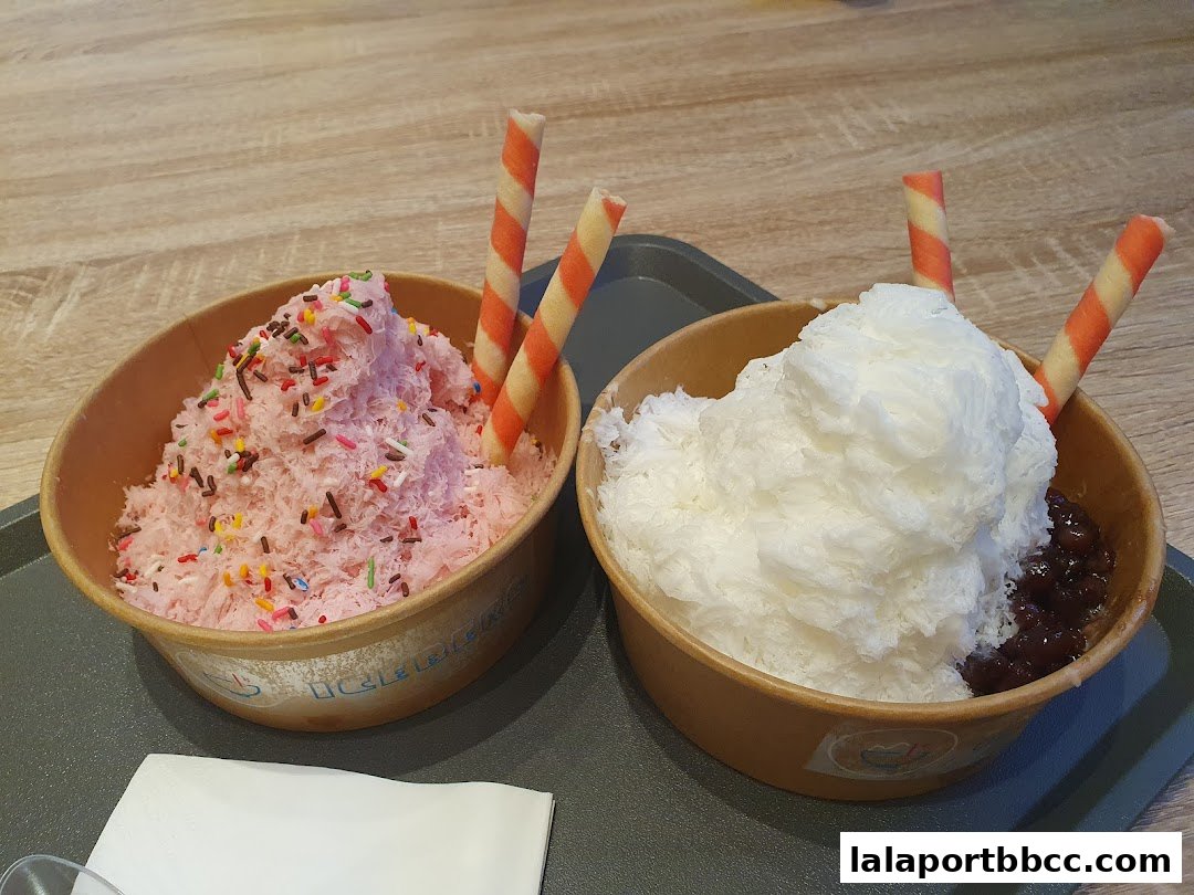 Two bowls of shaved ice desserts, one pink with sprinkles and one white with red beans, garnished with wafer sticks.