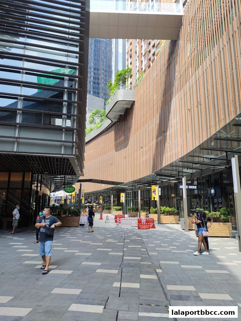 People walking in a modern outdoor shopping arcade with contemporary architecture.