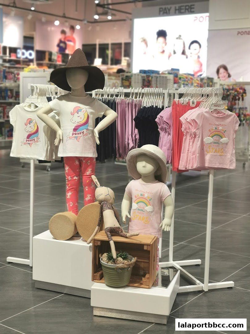 Children's clothing displayed on mannequins with a 'Pay Here' sign in the background.