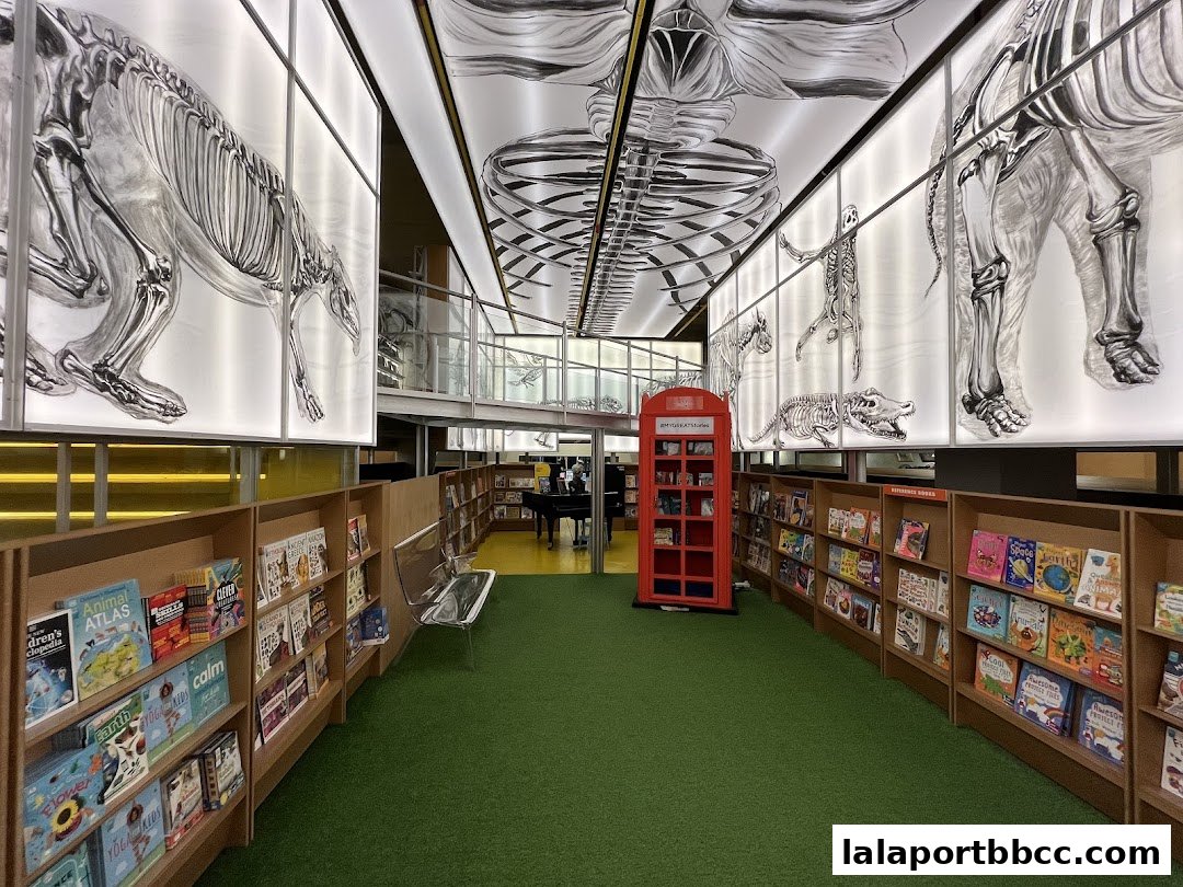 Interior of a bookstore with shelves of books, skeleton art on the ceiling, and a red phone booth.