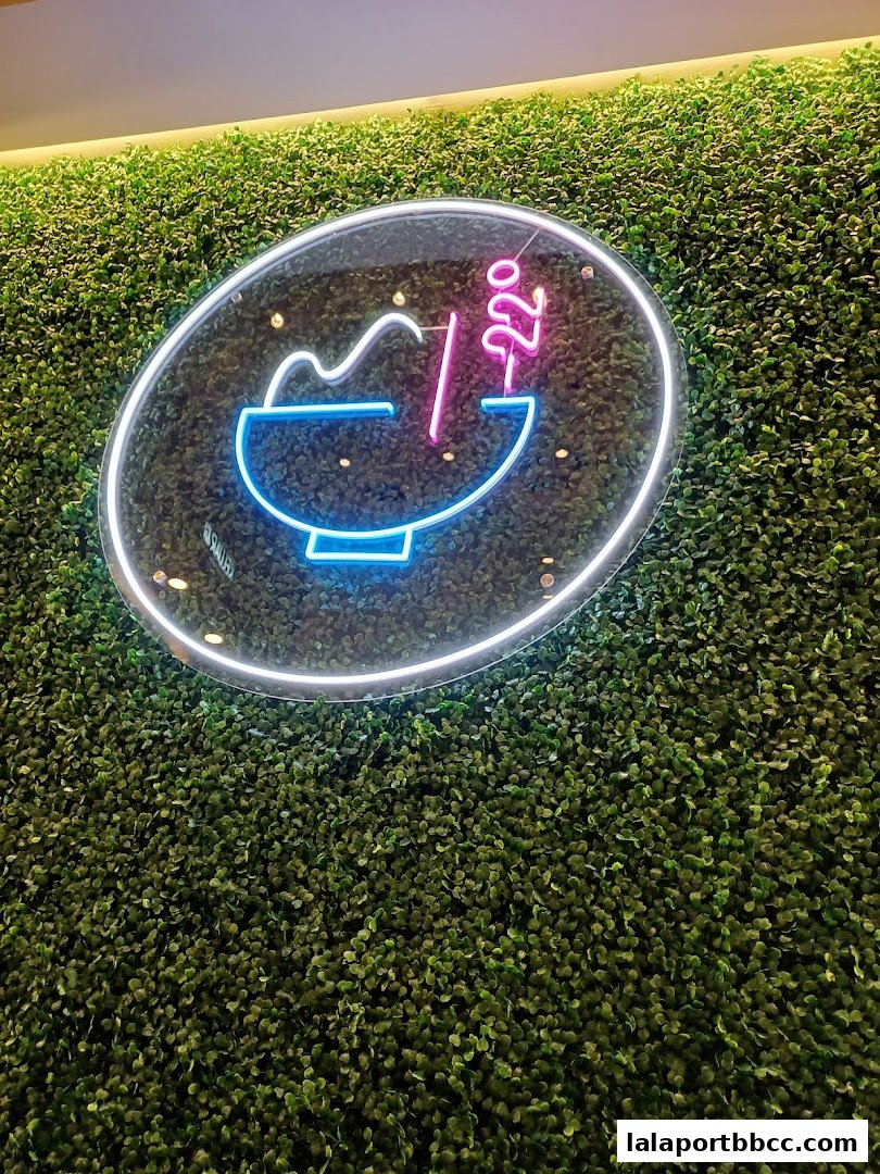 A neon sign depicting a bowl of food with "-22°" on a green wall.