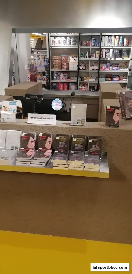 A retail counter with books displayed, an information desk, and shelves stocked with various items.