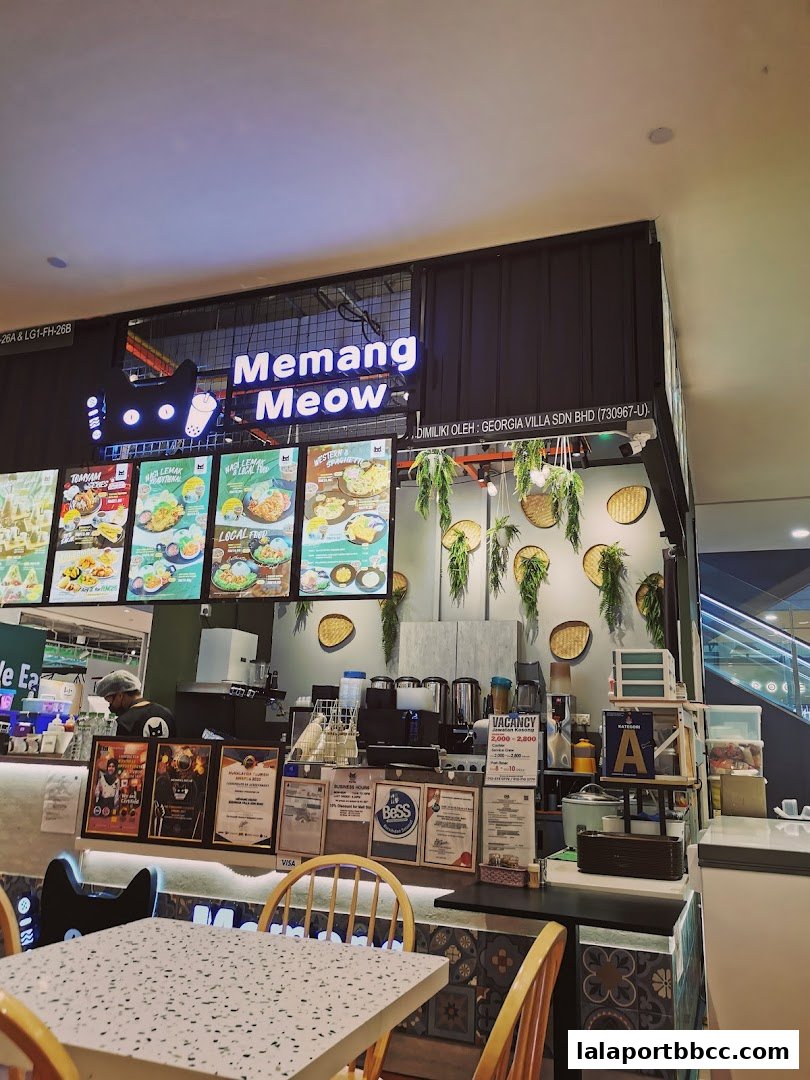 The front of a food stall with a neon sign and menu displays.