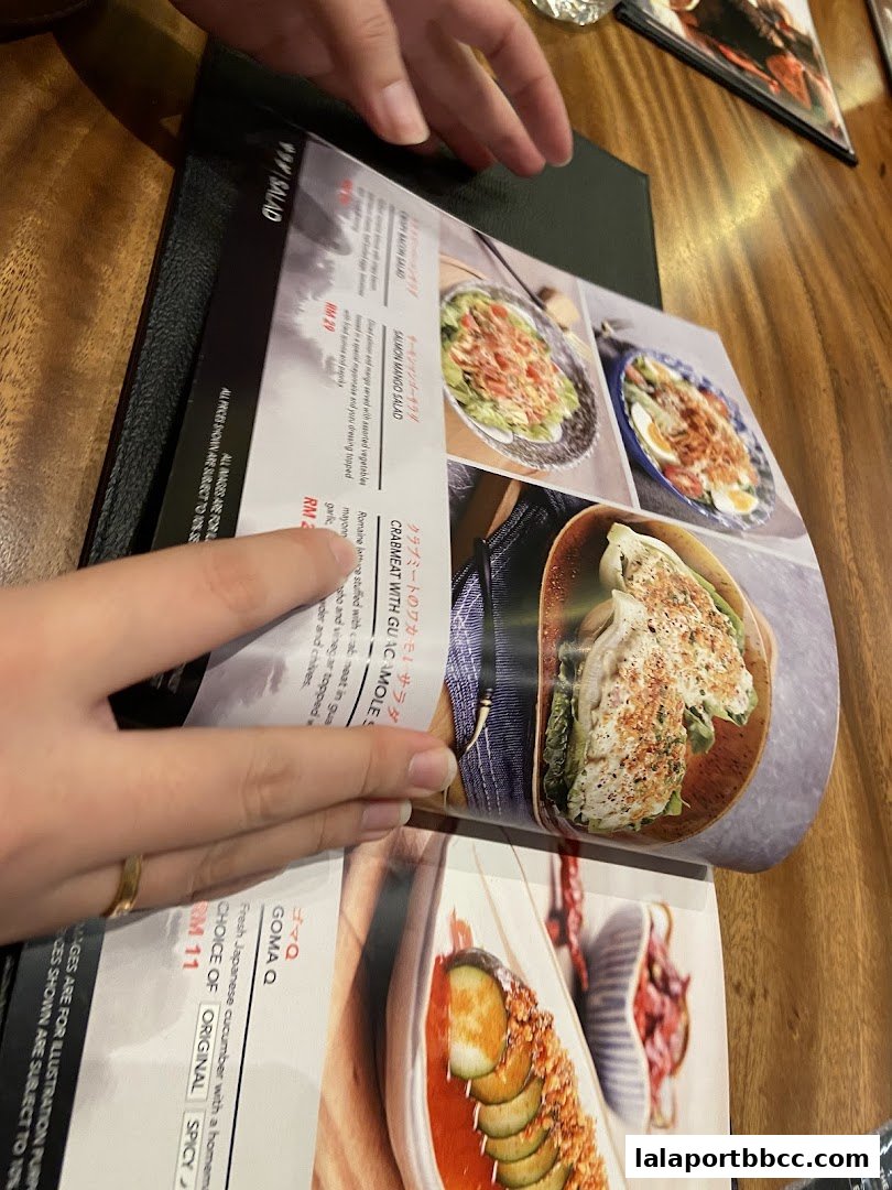 A person's hands are holding open a menu with pictures of salads and other dishes.