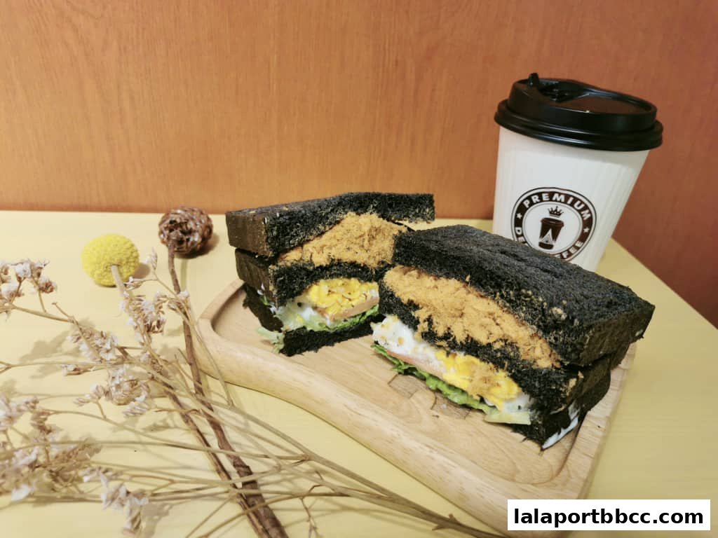 A charcoal sandwich with shredded meat and egg, served with a coffee cup.