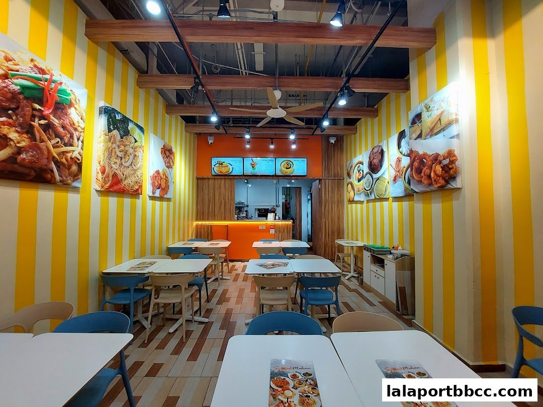 Interior of a brightly lit restaurant with yellow and white striped walls and food images.