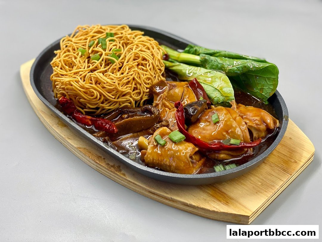 A sizzling hot plate dish with crispy noodles, chicken, mushrooms, and greens.