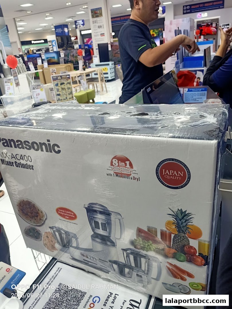 A Panasonic mixer grinder box is displayed in a retail store with electronics in the background.