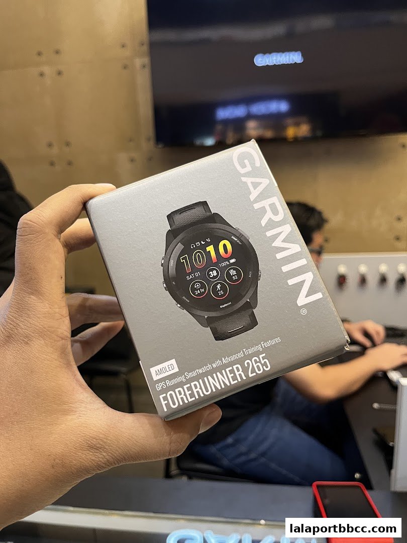 A hand holds a box for a Garmin Forerunner 265 GPS running smartwatch.
