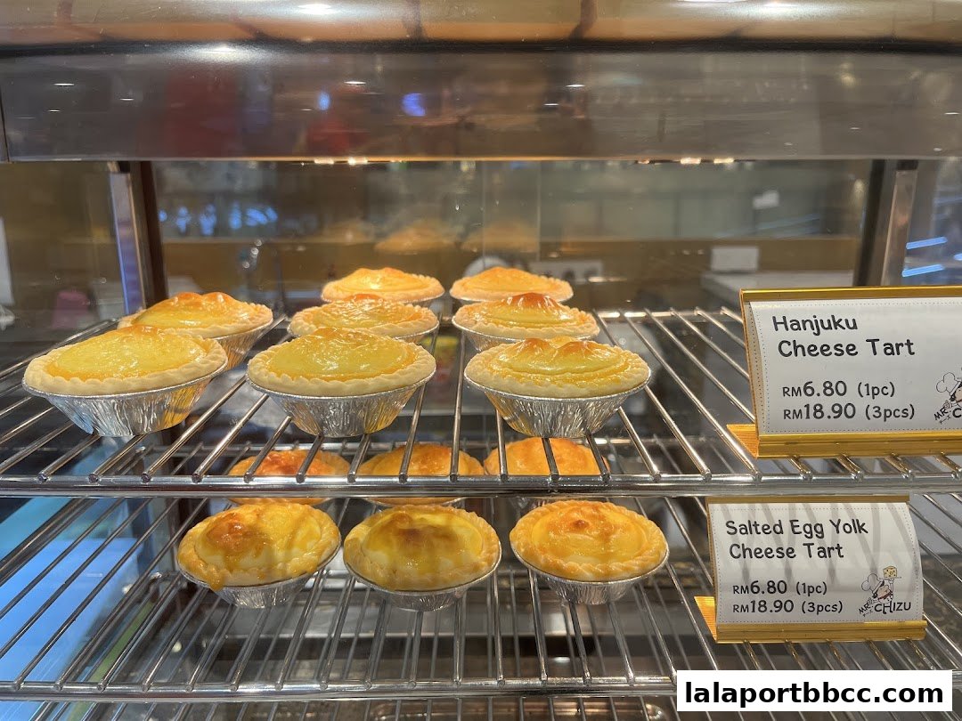 A display of freshly baked cheese tarts in a refrigerated showcase.
