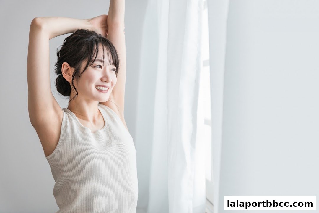 A young woman with her arms stretched upwards, smiling and looking to the side.