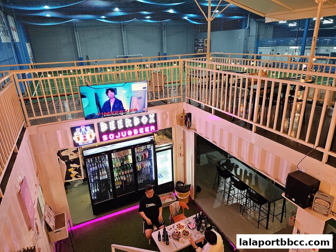 Interior view of Beer Box, a casual establishment with a bar, seating, and a sports screen.