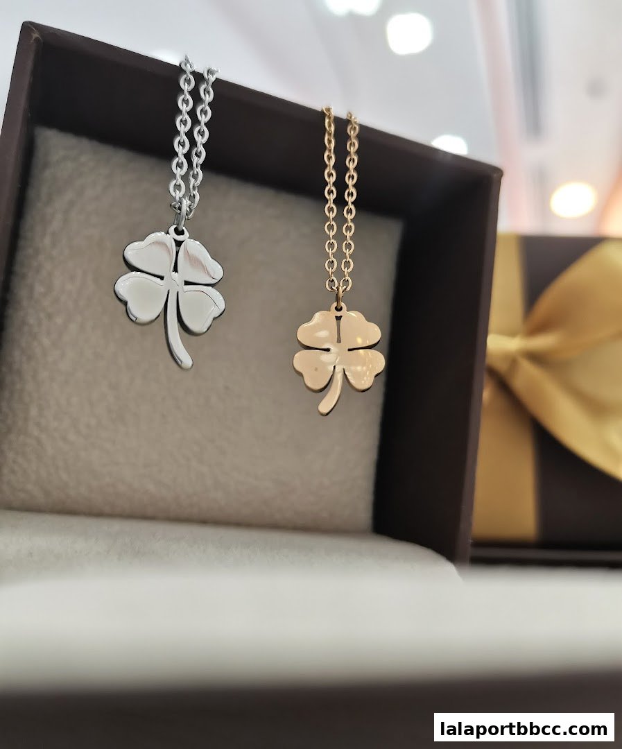 Two delicate four-leaf clover necklaces, one silver and one gold, displayed in a gift box.