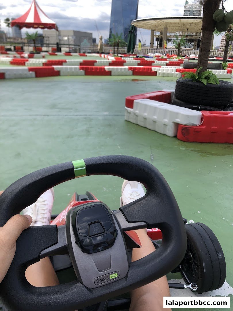 A first-person view of a go-kart steering wheel on a race track.