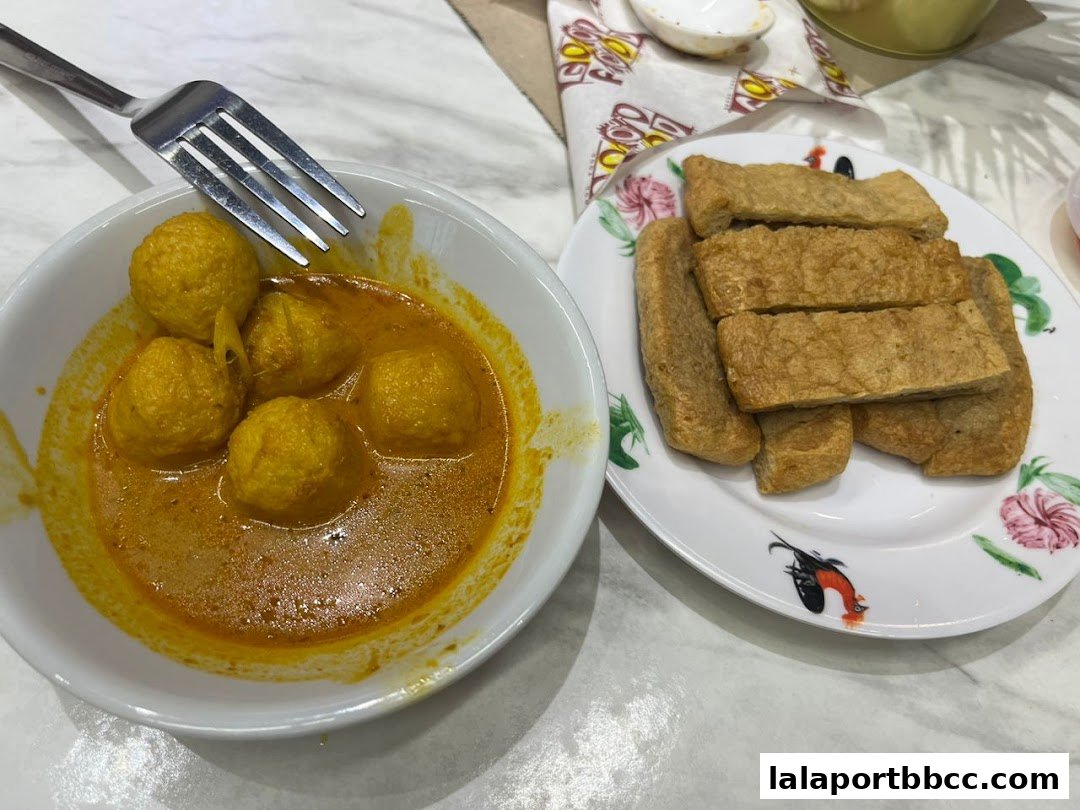 A bowl of curry fish balls and a plate of fried fish cakes, ready to be eaten.
