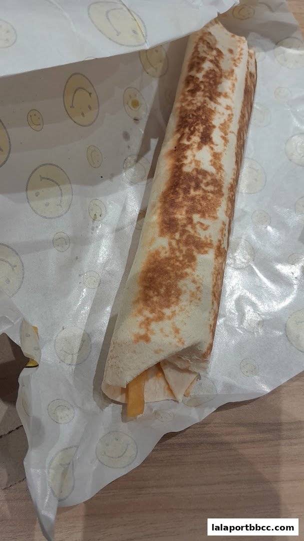 A delicious-looking kebab wrap, neatly rolled and presented on branded paper.