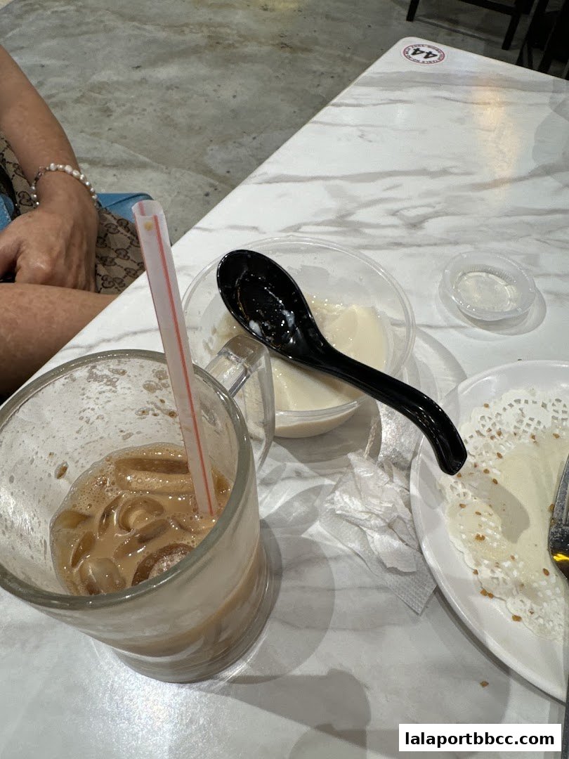 A close-up of a table at Sai Kee Restaurant with iced coffee and dessert.