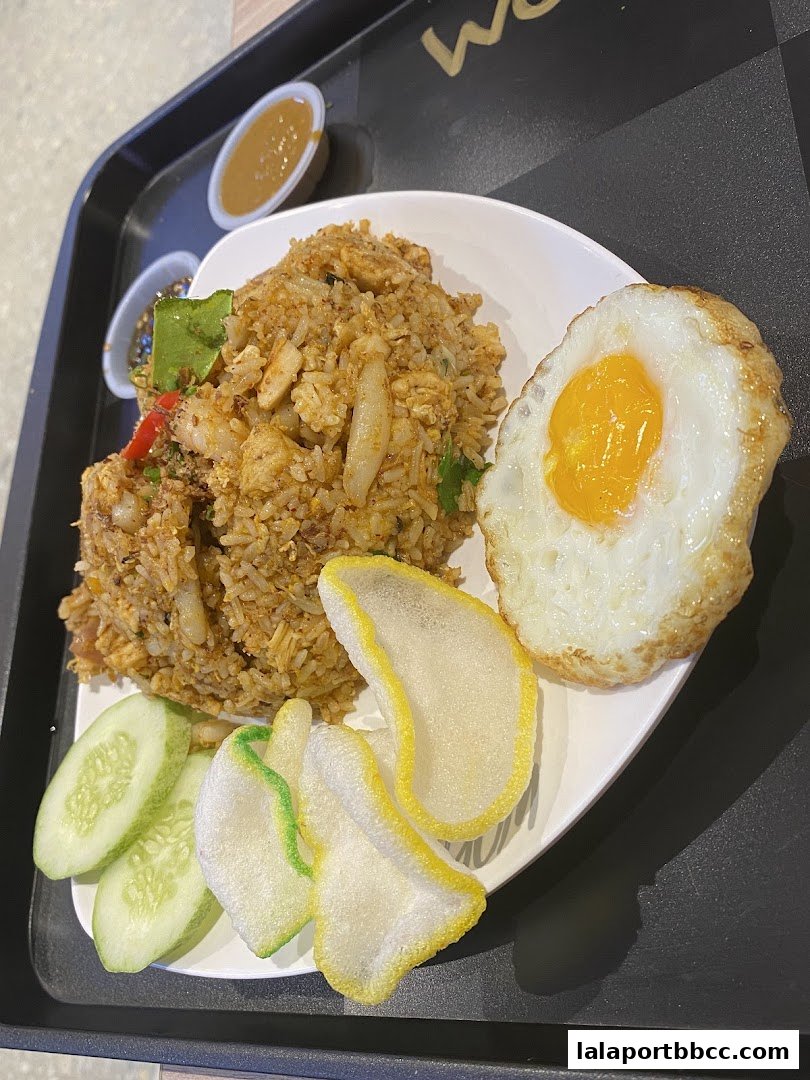 A plate of nasi goreng with a fried egg, cucumber slices, and crackers on a tray.