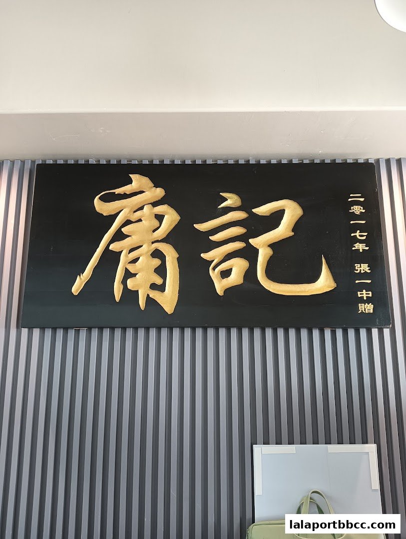 A golden sign with Chinese characters hangs on a grey slatted wall.