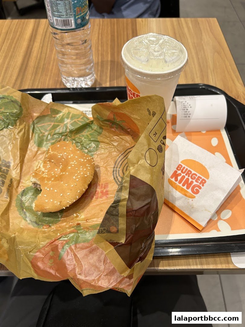 A Burger King meal with a partially eaten burger, fries, drink, and receipt on a tray.