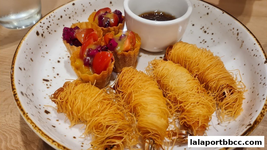 A plate of crispy fried shrimp and fruit tarts served with a dipping sauce.