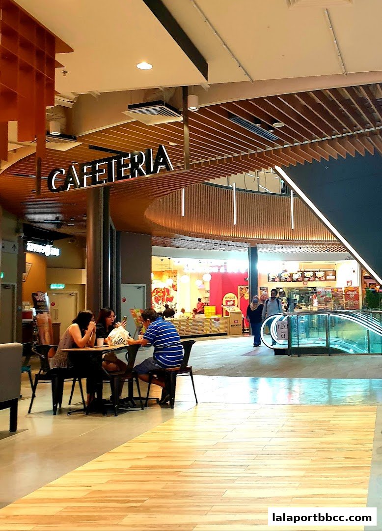 People dining at tables in a modern cafeteria with a prominent 'CAFETERIA' sign.