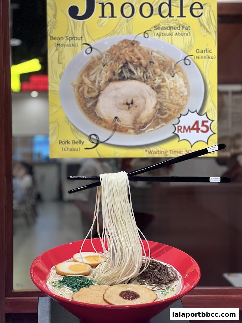 A realistic ramen display with chopsticks holding noodles above a bowl.