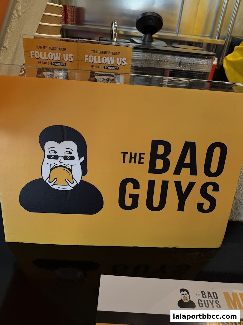 A bright yellow sign with the logo 'The Bao Guys' and a cartoon character eating a bao.
