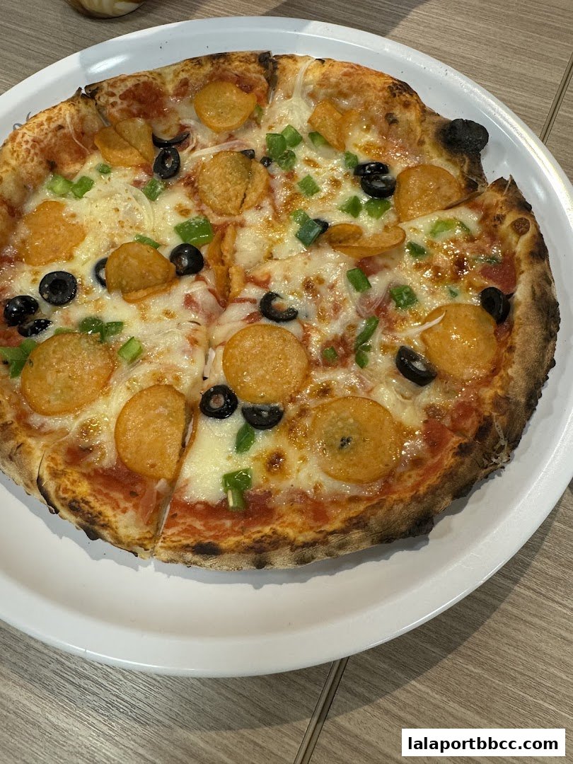 A delicious pizza with pepperoni, olives, and green peppers on a white plate.