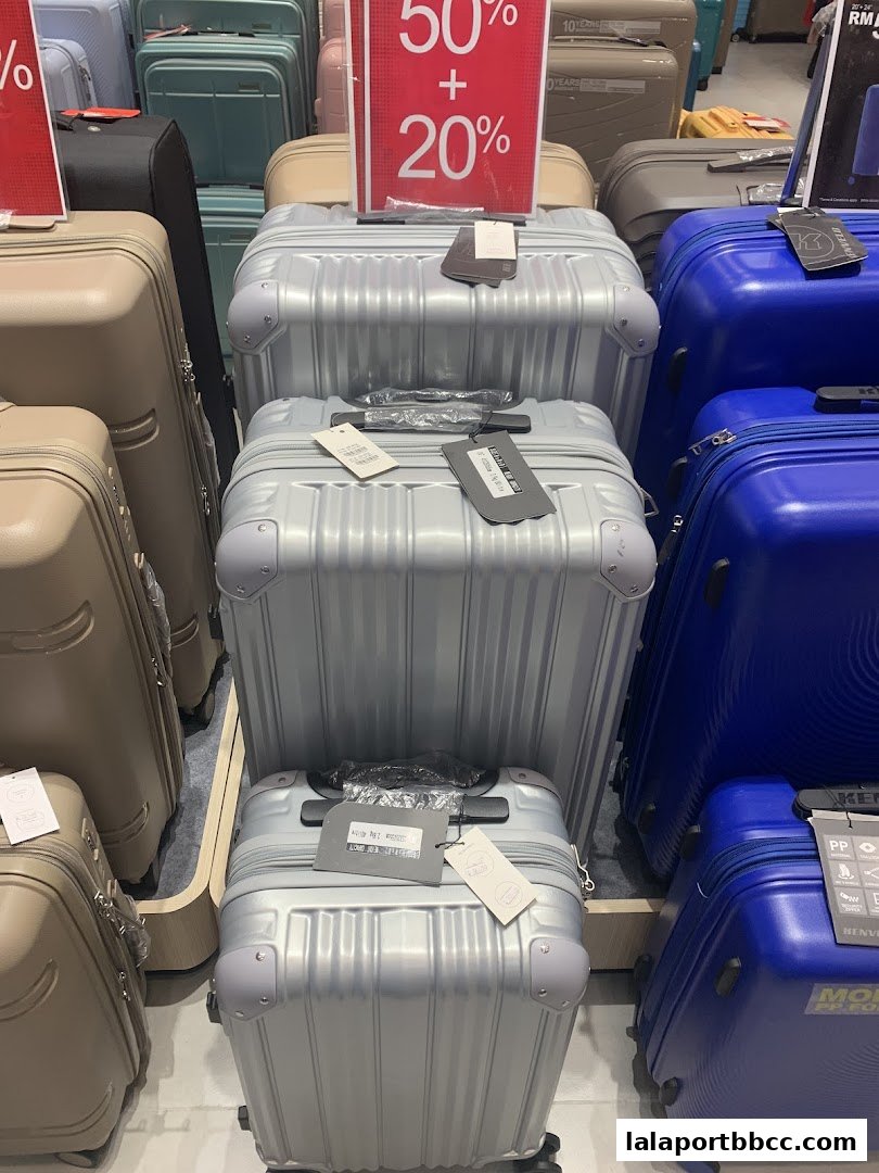 A display of various suitcases in different colors, with a sale sign indicating discounts.