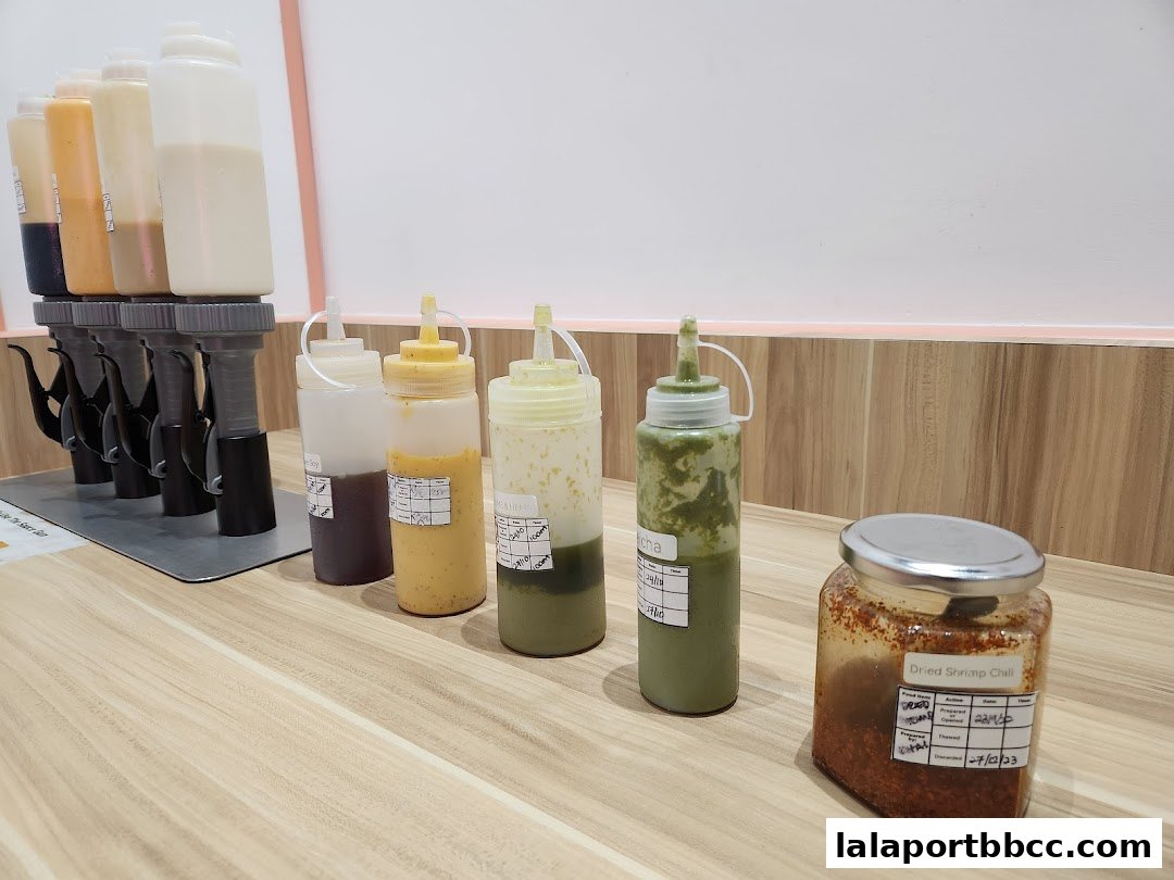 A selection of sauces and a jar of dried shrimp chili on a wooden counter.