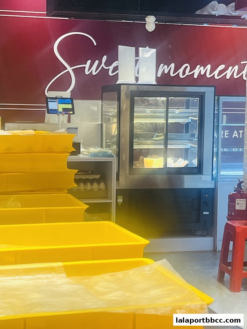 A bakery interior with yellow trays, a display fridge, and a cash register.