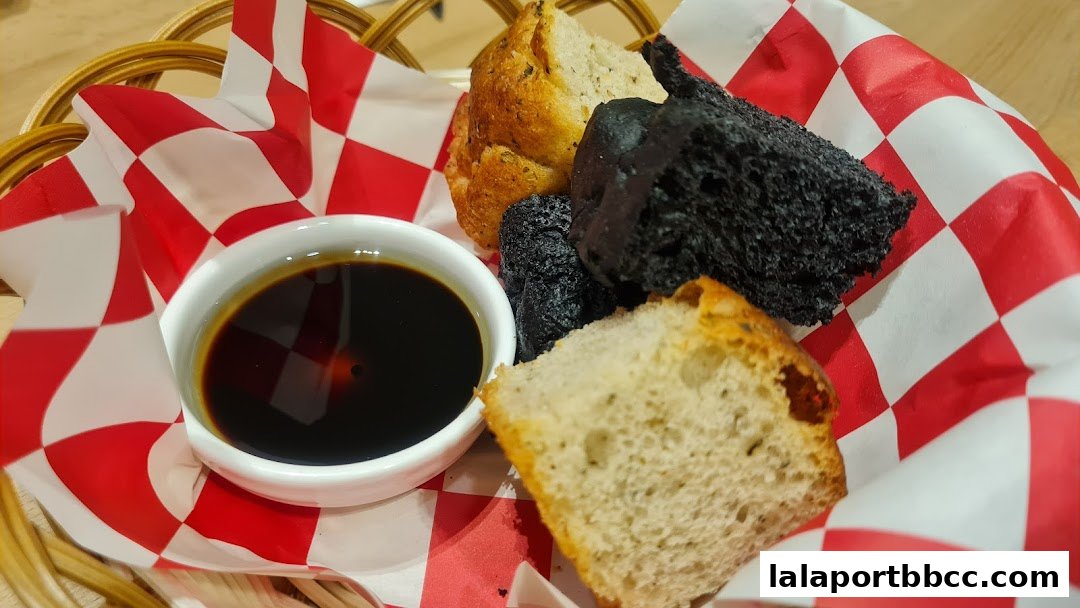 A basket of assorted bread pieces with a small bowl of dark sauce.