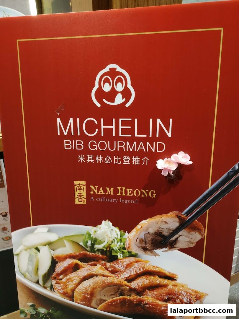 A sign for Nam Heong Chicken Rice, featuring a Michelin Bib Gourmand award and a plate of roasted chicken.